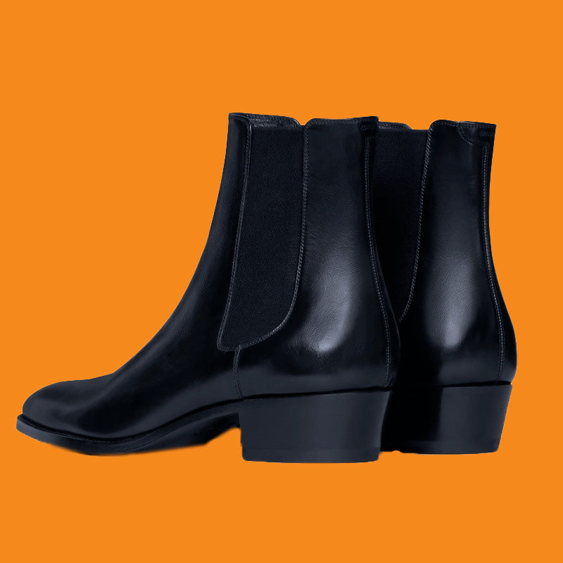 Black leather ankle boots on an orange background