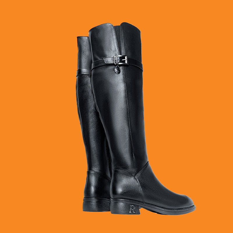 Black knee-high boots with a buckle on an orange background