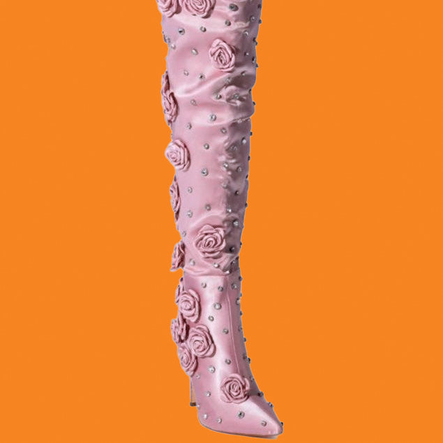 Pink knee-high boot with floral and pearl details on an orange background
