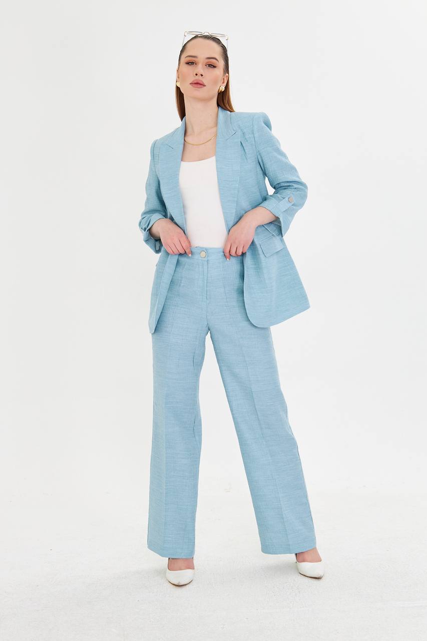 Woman wearing a light blue suit with a white top on a white background