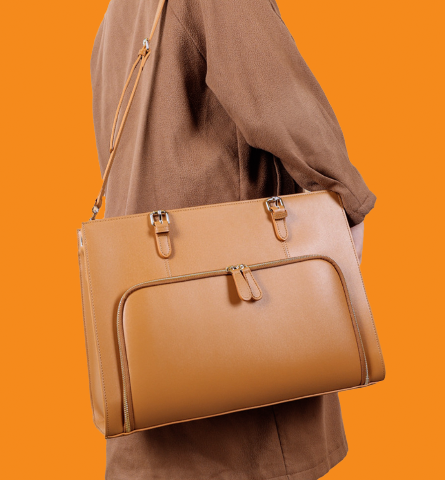 Brown leather handbag carried by a person on an orange background