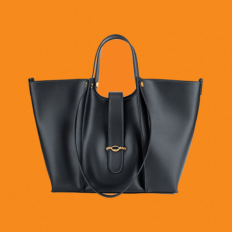 Black handbag with gold clasp on an orange background