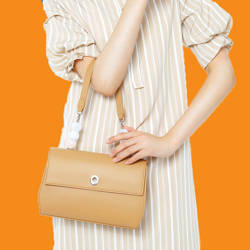Person holding a beige handbag against an orange background