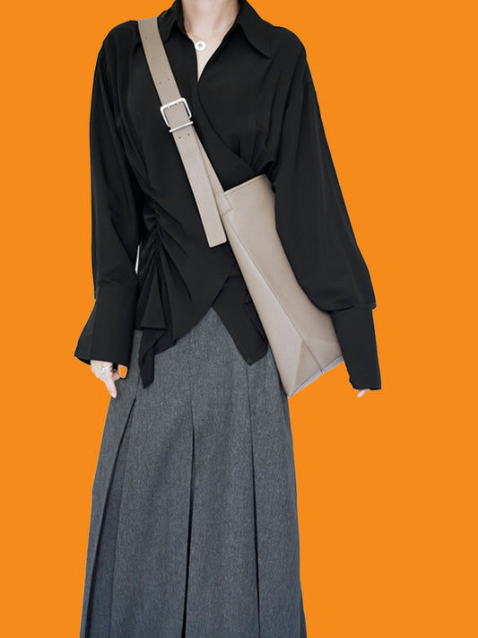 Person wearing a black shirt and gray pants with a beige crossbody bag on an orange background