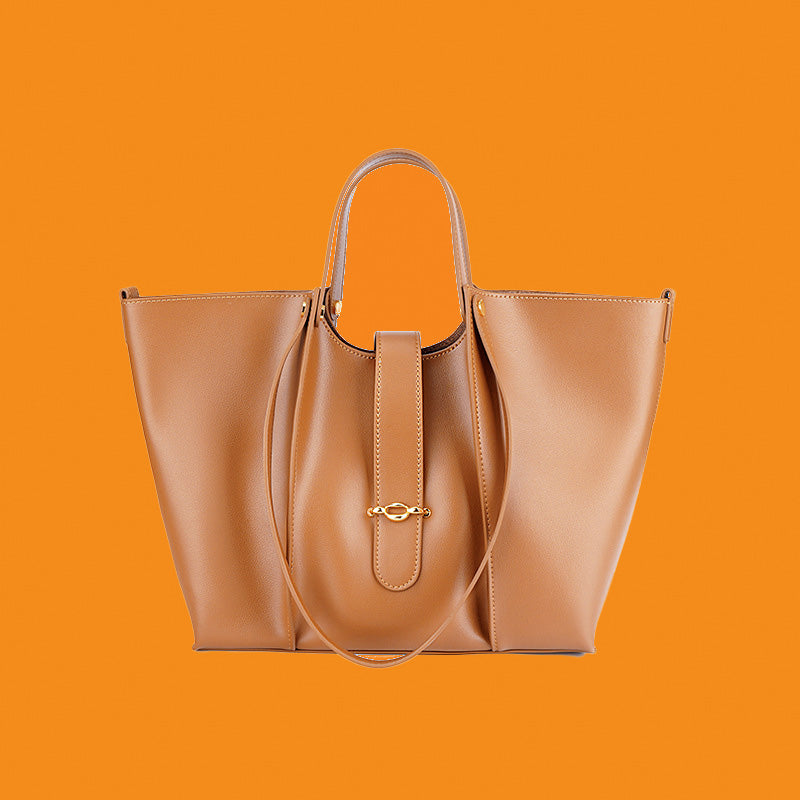 Tan leather handbag with a gold clasp on an orange background