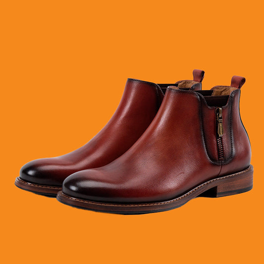 Pair of brown leather boots with a zipper on an orange background