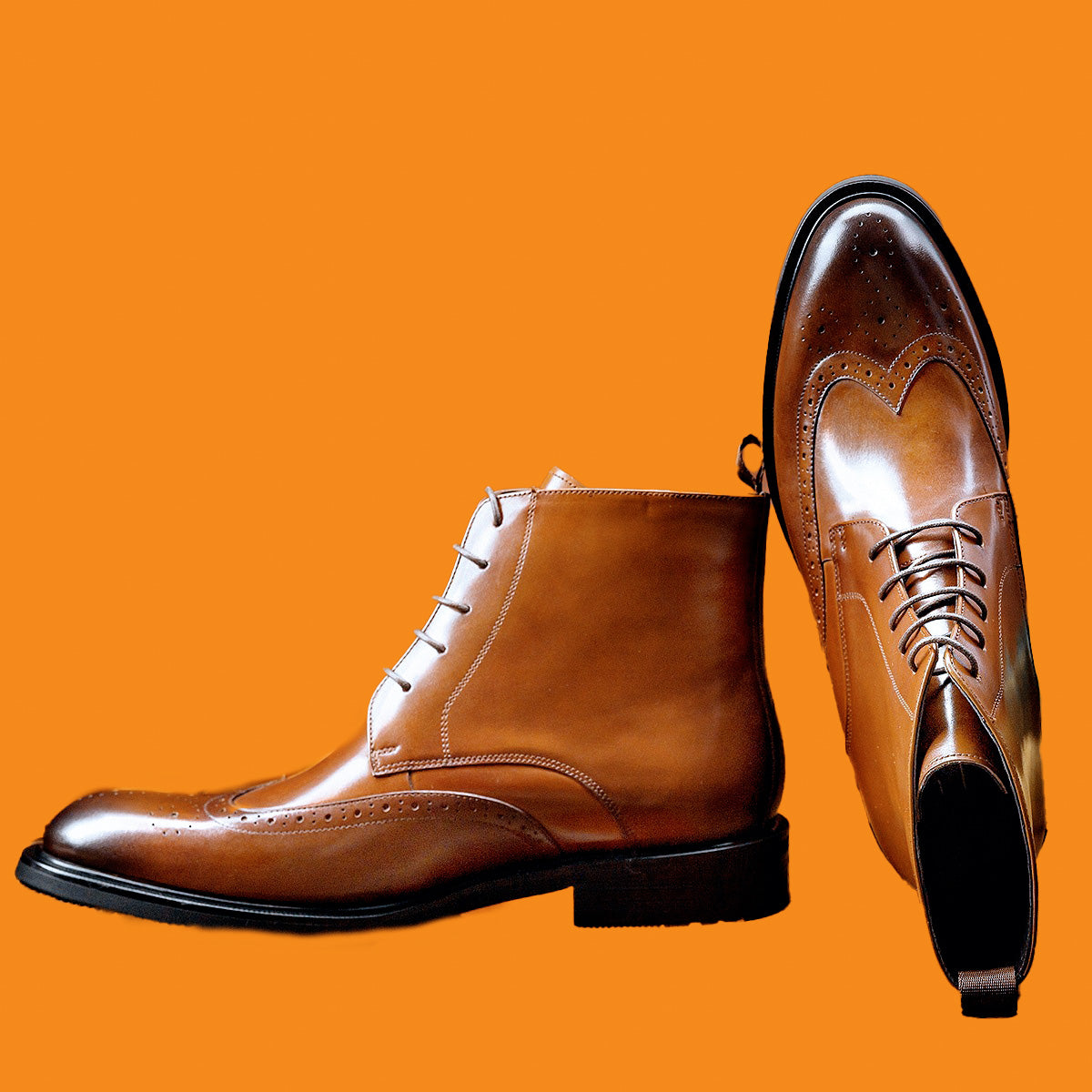 Pair of brown leather dress shoes on an orange background