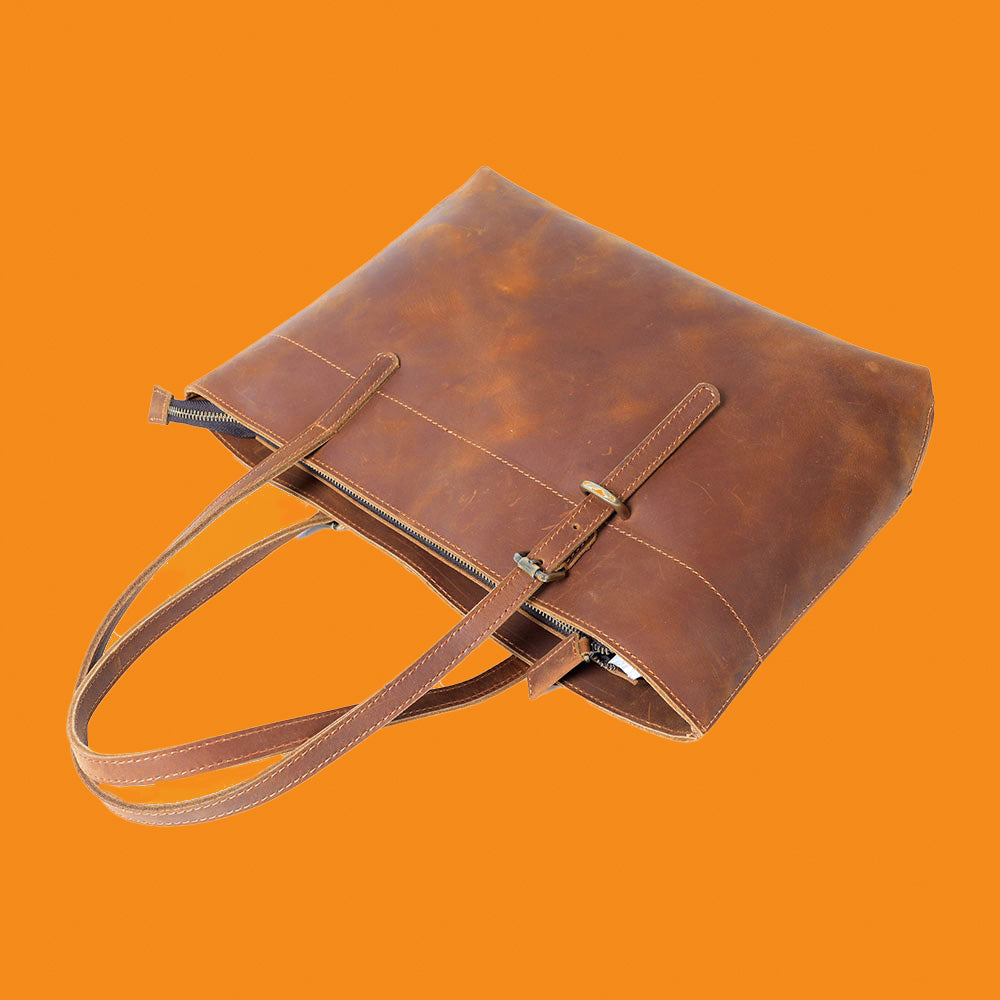 Brown leather tote bag on an orange background