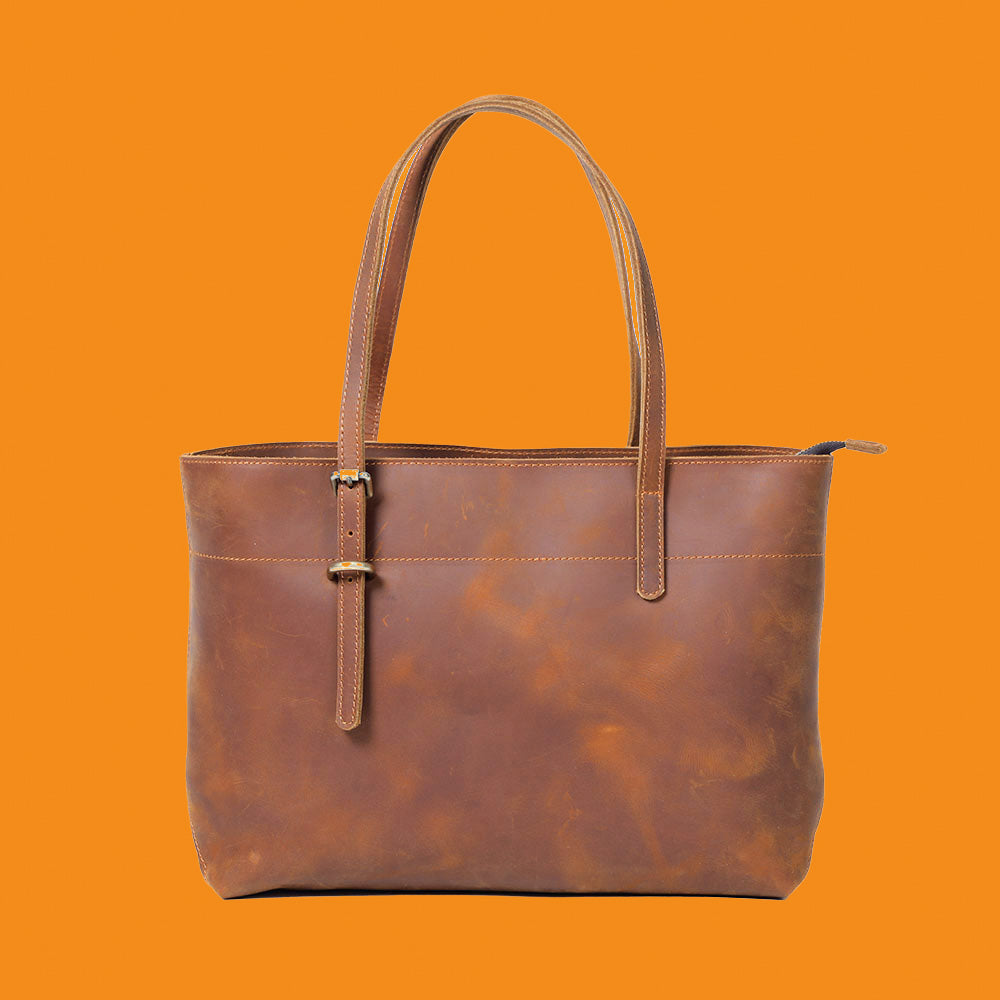 Brown leather tote bag on an orange background