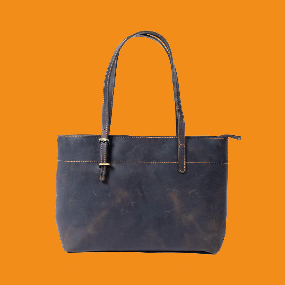 Blue leather tote bag on an orange background