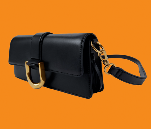 Black handbag with gold hardware on an orange background
