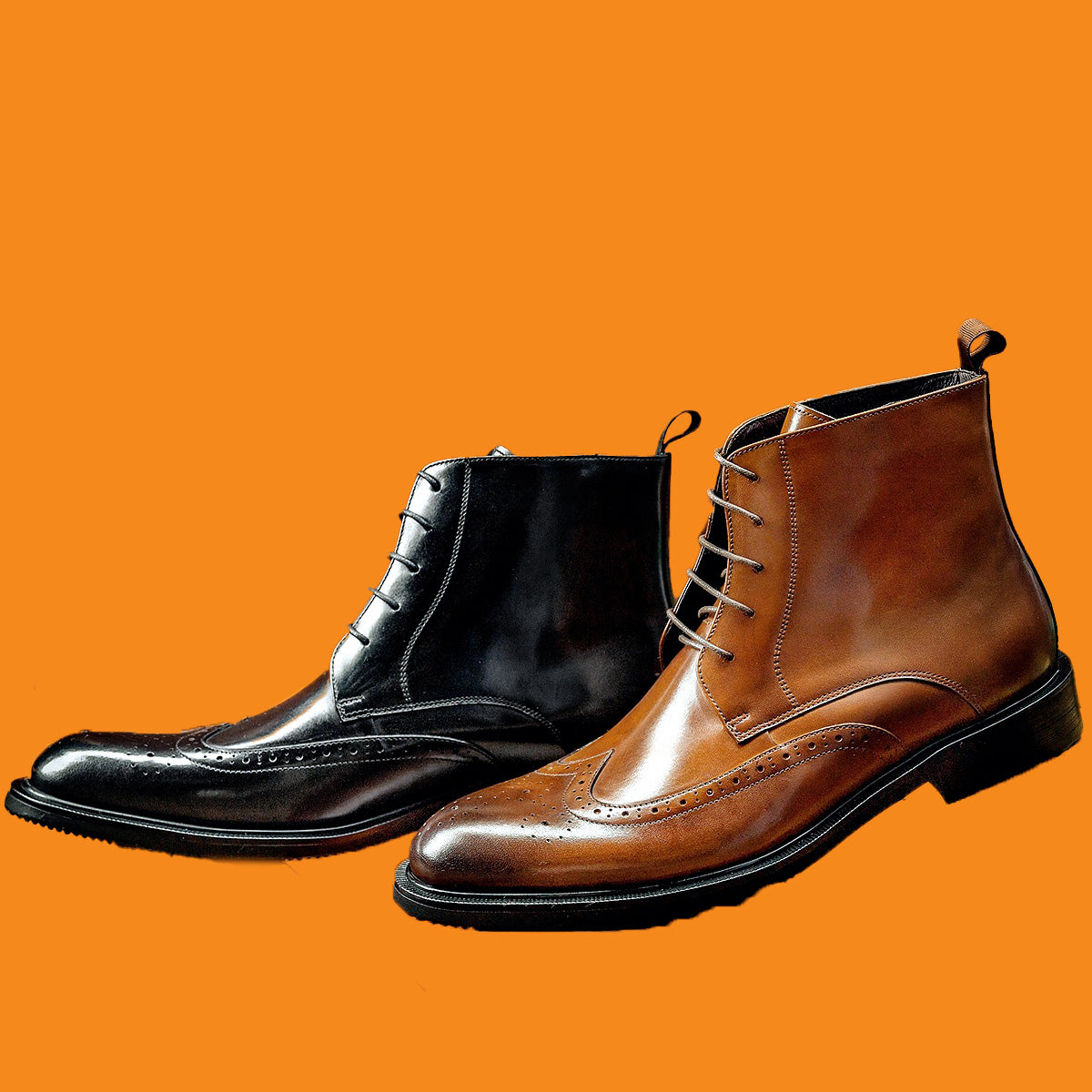 Pair of black and brown leather boots on an orange background