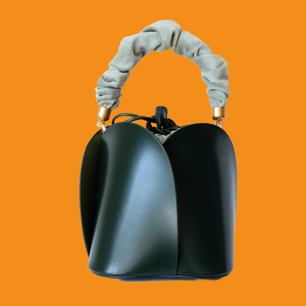 Black handbag with a textured handle on an orange background
