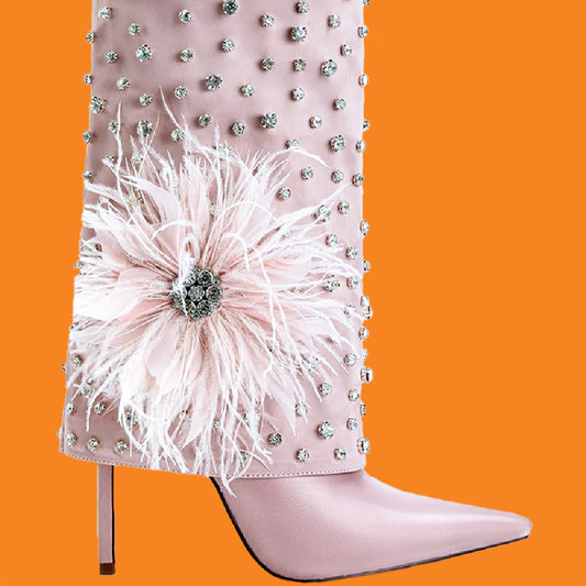Pink boot with decorative flower and embellishments on an orange background