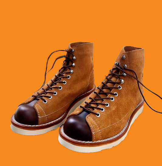 Brown leather boots with black soles on an orange background