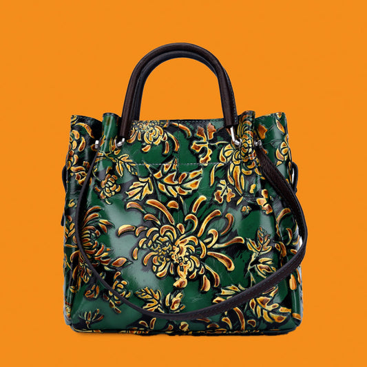 Green handbag with gold floral patterns on an orange background