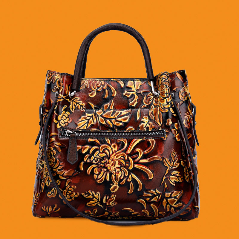Brown handbag with gold floral patterns on an orange background