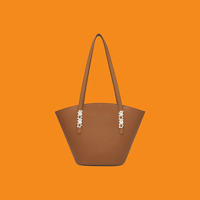 Brown handbag with decorative elements on an orange background