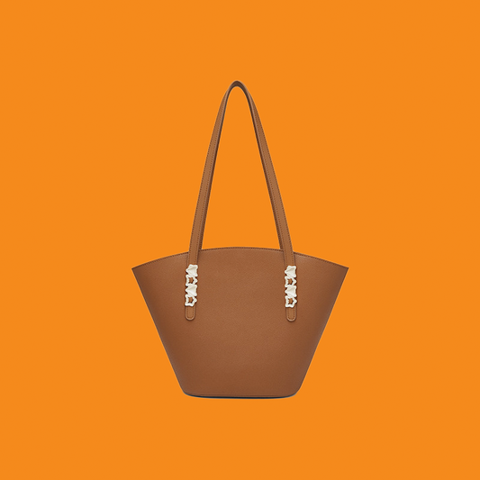 Brown handbag with decorative elements on an orange background