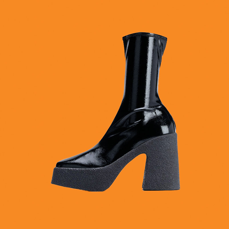 Black patent leather boot with a chunky heel on an orange background