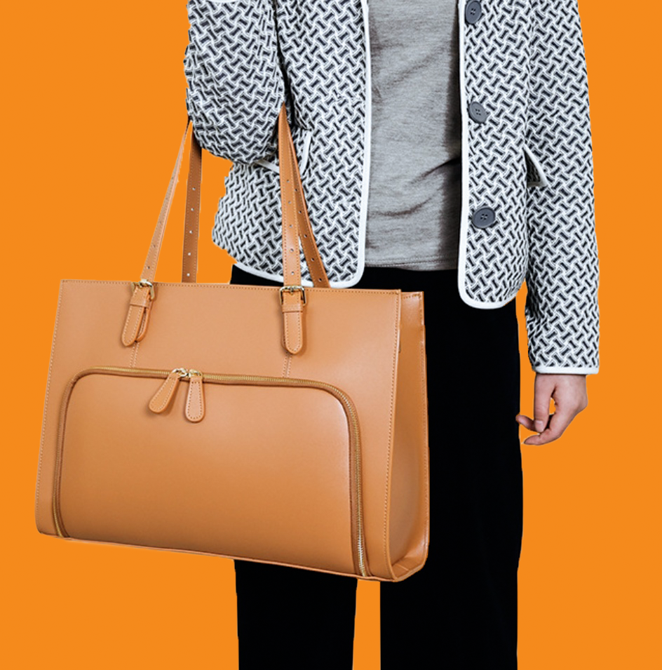 Person holding a brown leather handbag against an orange background