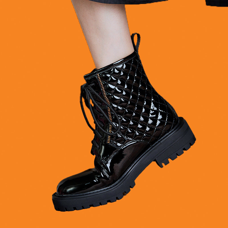Black patent leather boot with a thick sole on an orange background