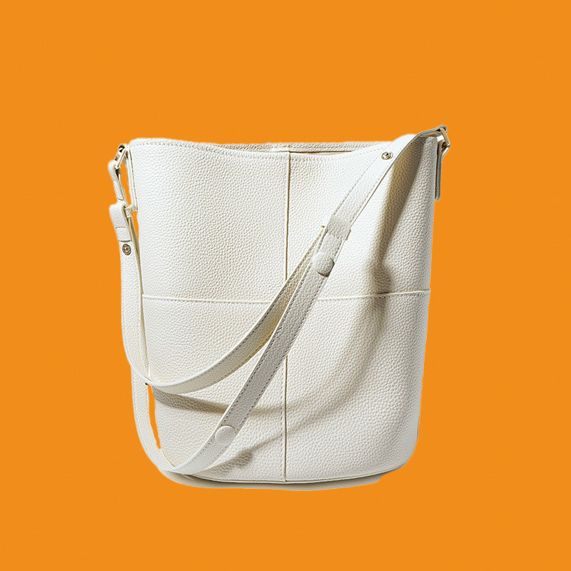 White leather handbag with a strap on an orange background