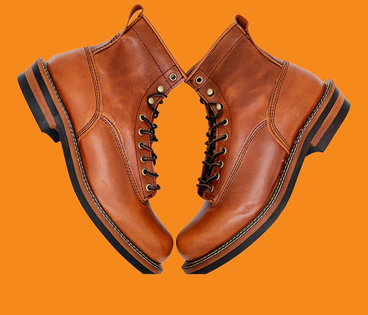 Pair of brown leather boots on an orange background