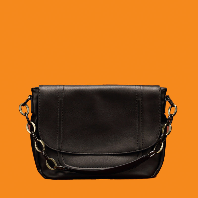 Black leather handbag with chain details on an orange background