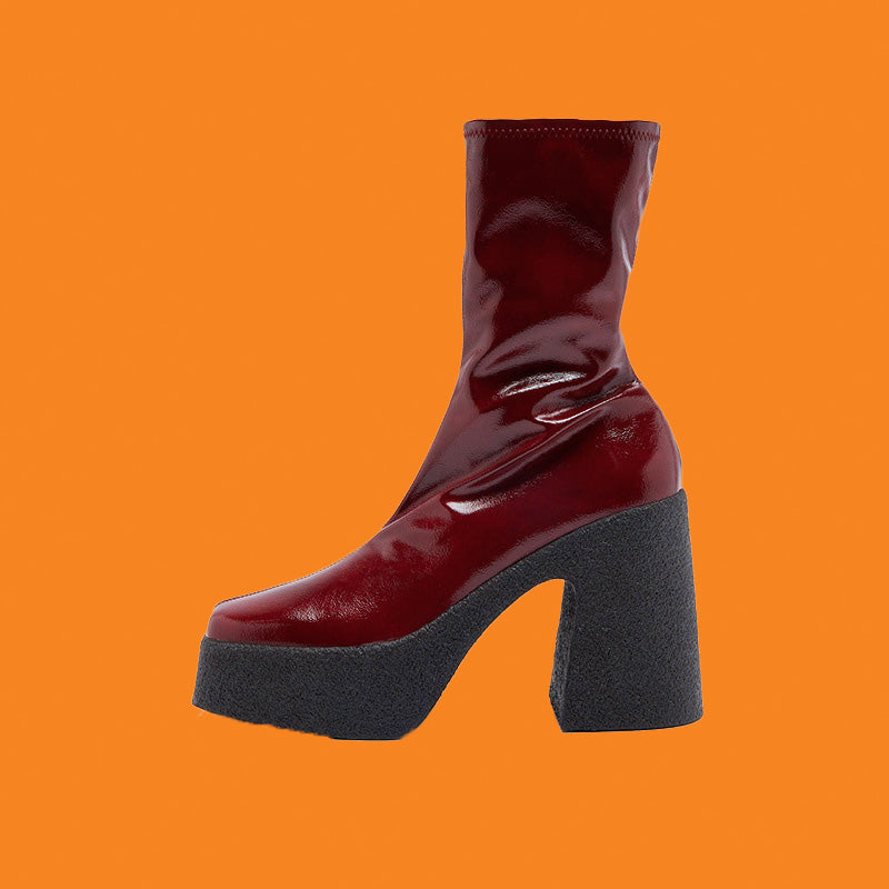 Shiny red boot with a thick black sole on an orange background