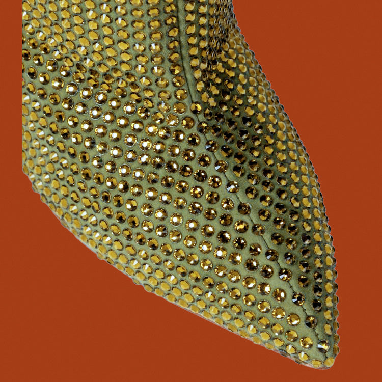 Green shoe with gold rhinestone embellishments on a red background
