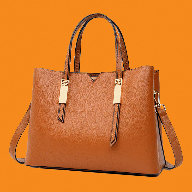 Brown leather handbag with gold accents on an orange background
