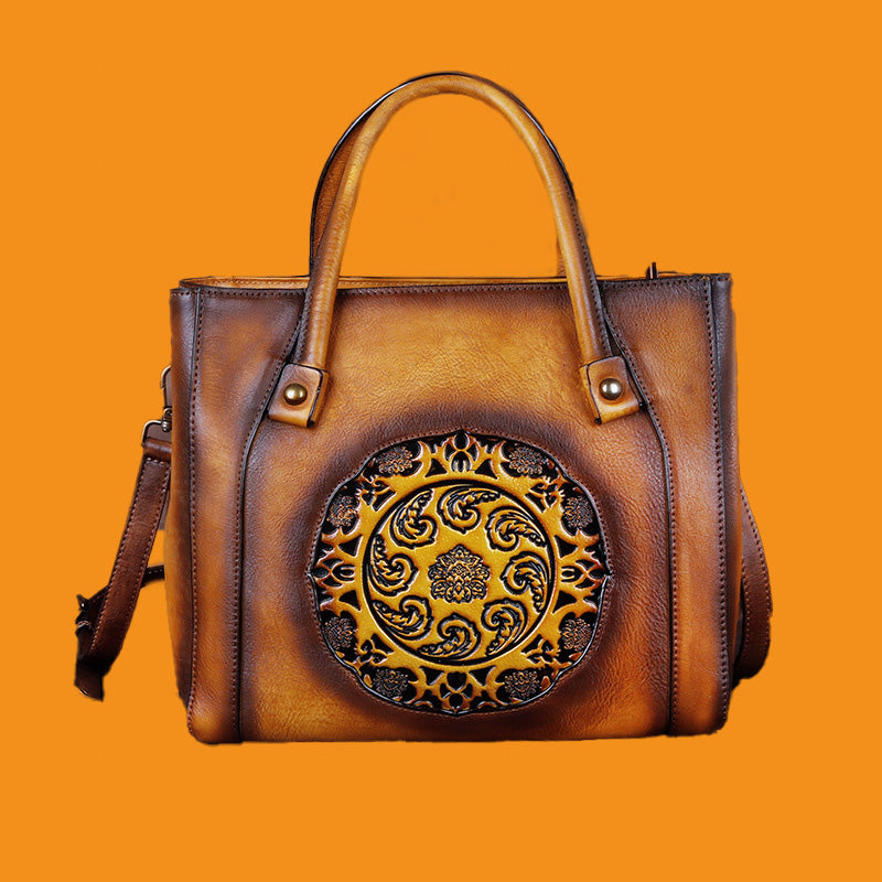 Brown leather handbag with decorative circular emblem on an orange background