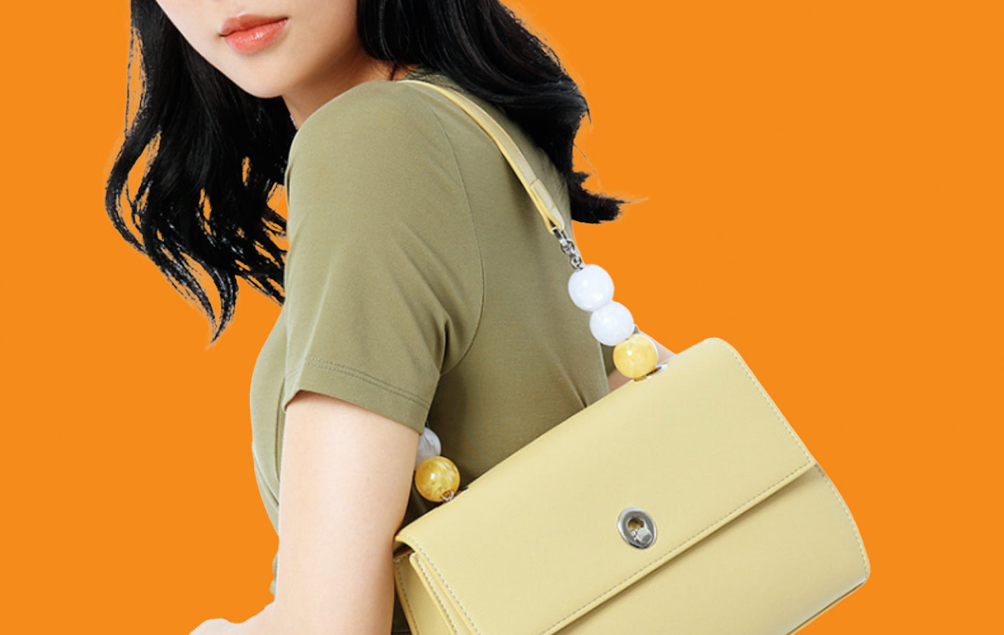 Woman carrying a yellow handbag against an orange background