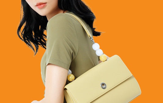 Woman carrying a yellow handbag against an orange background