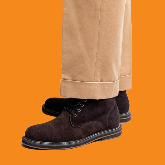Brown suede shoes worn with beige pants on an orange background