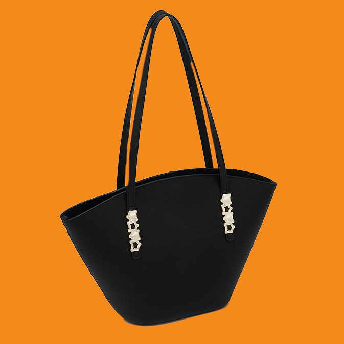 Black handbag with decorative elements on an orange background