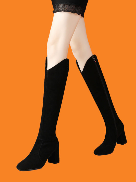 Black knee-high boots worn with white tights on an orange background