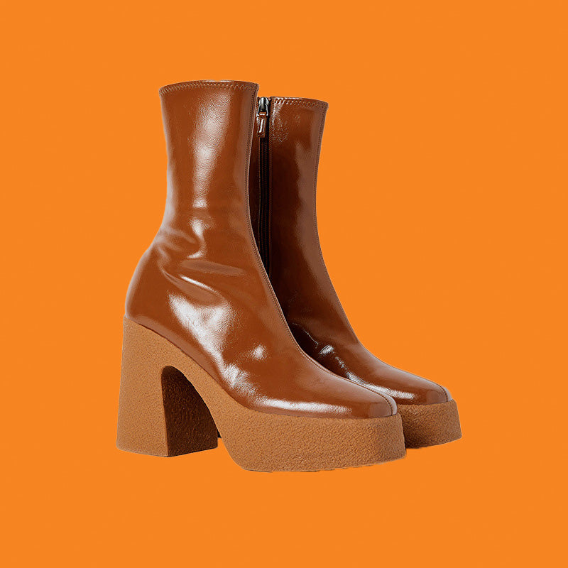Brown leather boots with chunky heels on an orange background