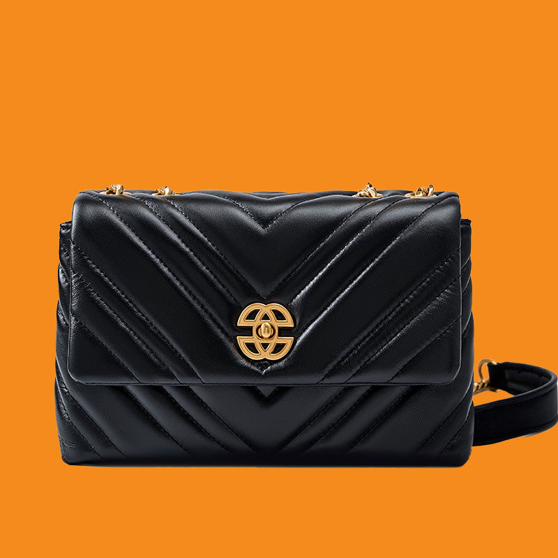 Black quilted handbag with gold emblem on an orange background