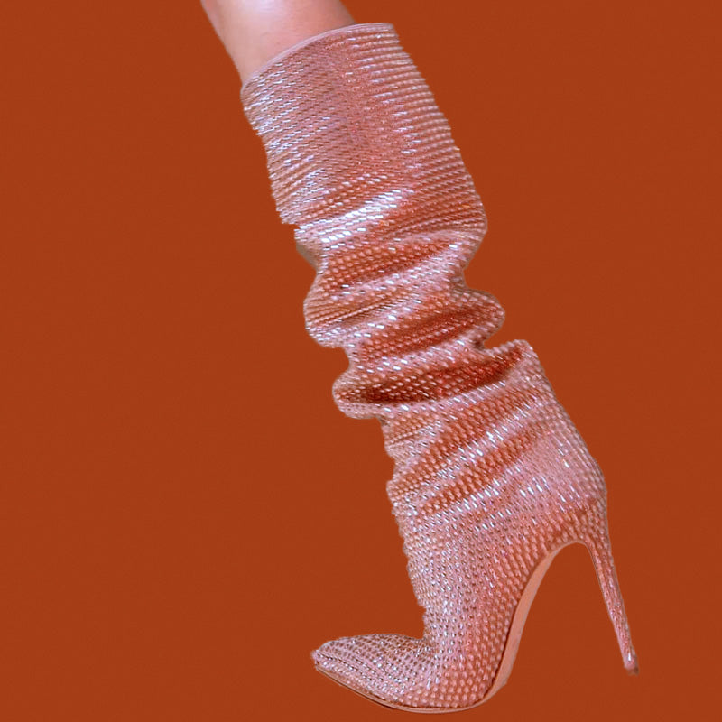 Rose gold stiletto heel boot on a solid orange background