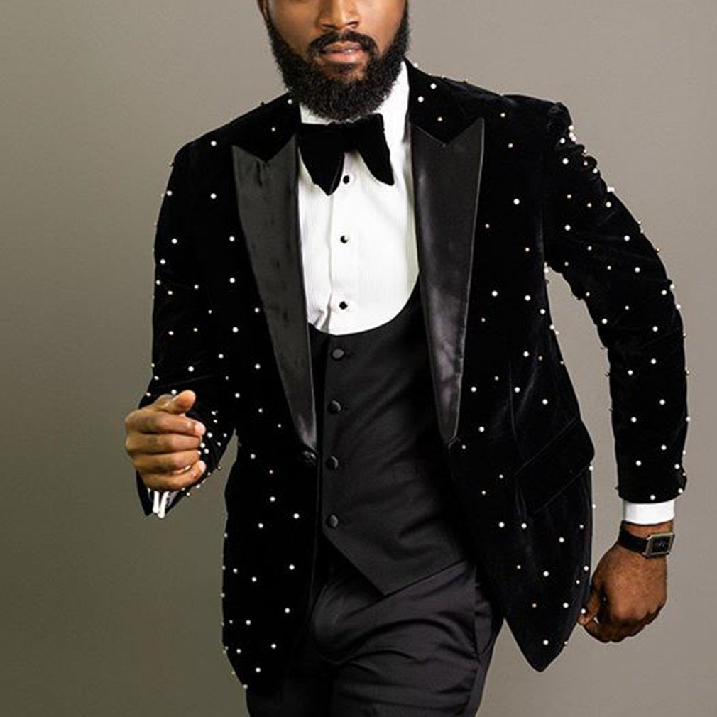 Man wearing a black tuxedo with white polka dots on a gray background