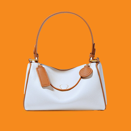 White handbag with brown handles and accents on an orange background