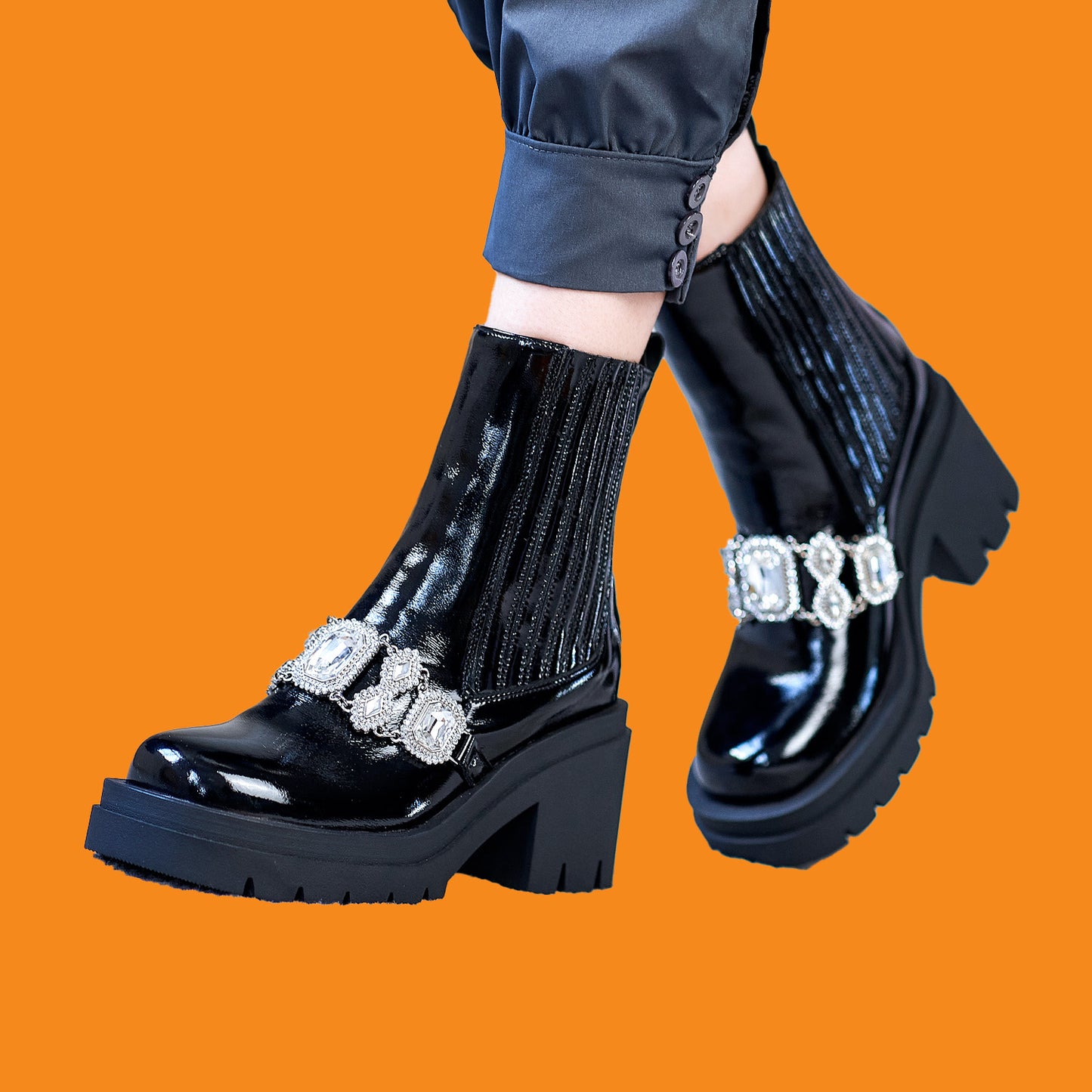 Black platform boots with decorative elements on an orange background