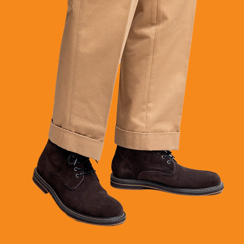 Brown suede shoes worn with beige pants on an orange background