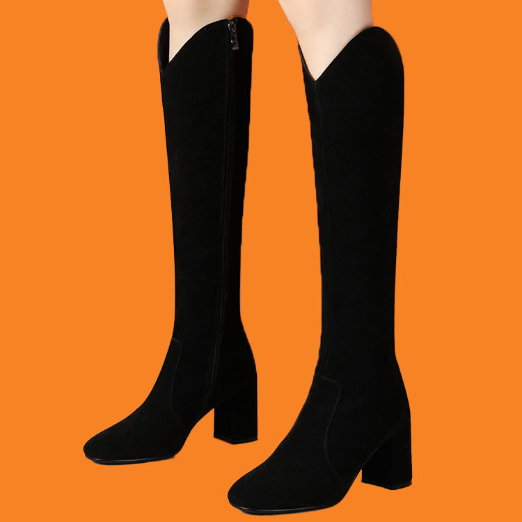 Black knee-high boots on a person against an orange background