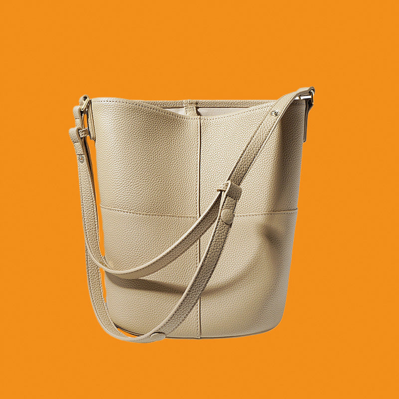 Beige leather handbag with a strap on an orange background
