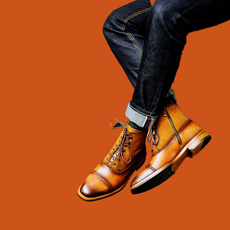 Brown leather shoes worn with dark jeans on an orange background