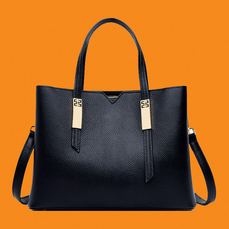Black leather handbag with gold accents on an orange background