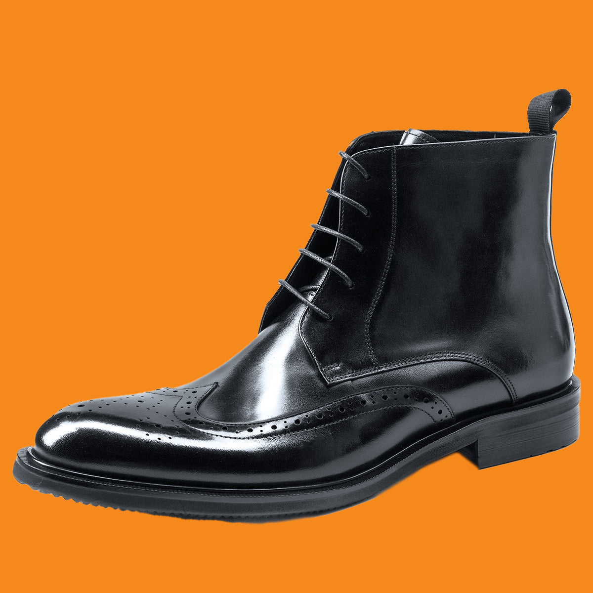 Black leather brogue boot on an orange background
